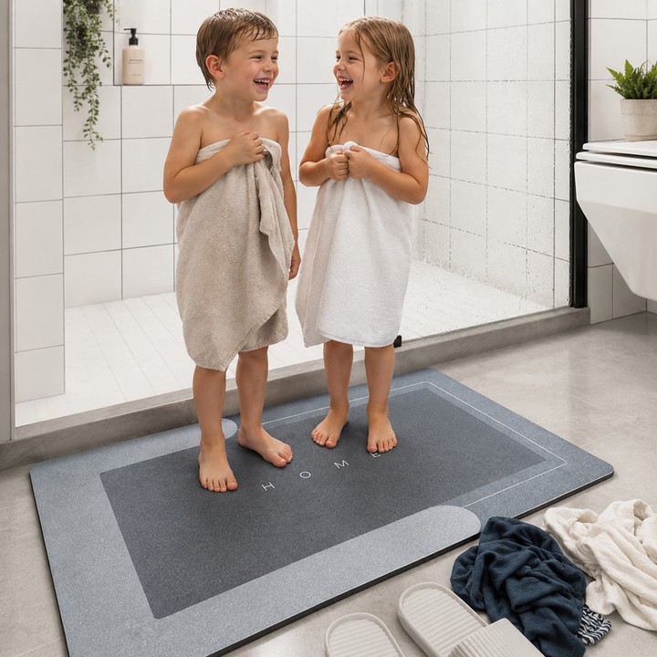 Two children standing on a large gray mat in a bathroom.
